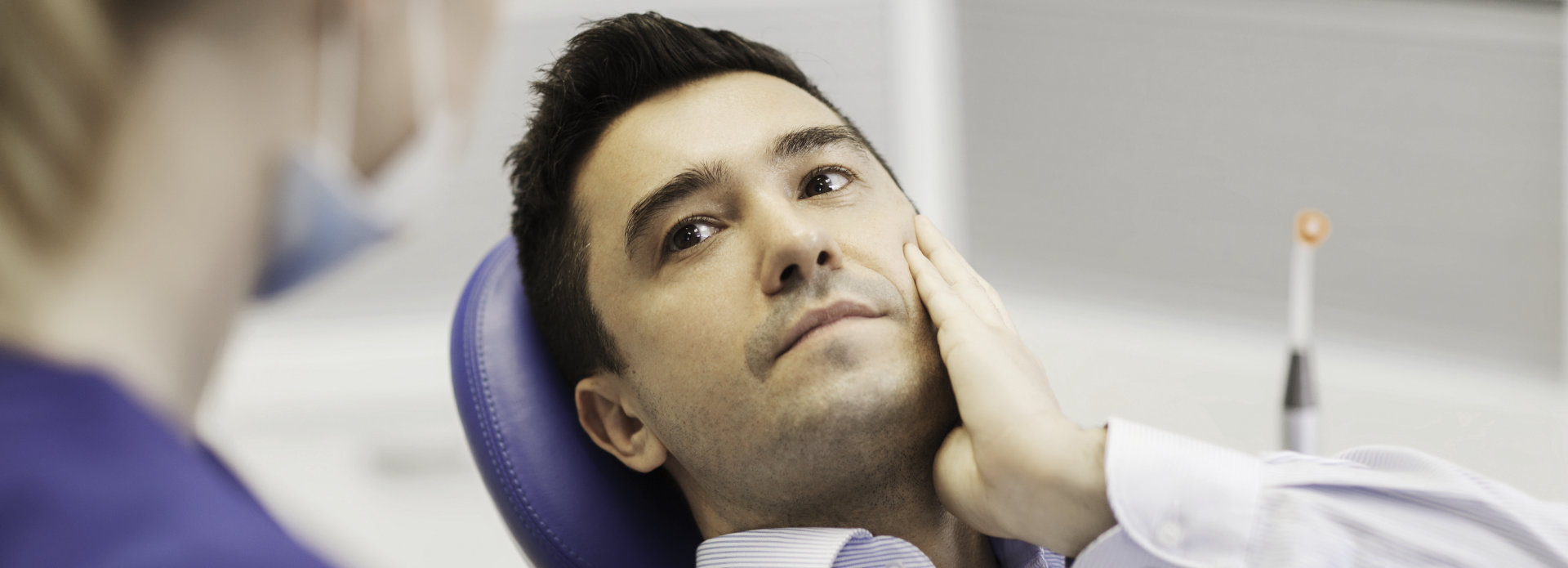Concerned man in a dental chair discussing cracked tooth repair with a dentist