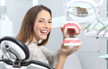 A woman smiles while holding a dental model.