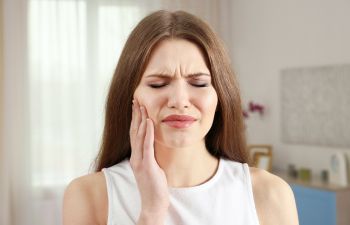 A woman with a toothache rubbing her cheek.