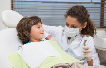 A pediatric dentist and a child in a dentist's chair.