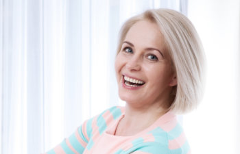 A smiling woman smiling in front of a window.