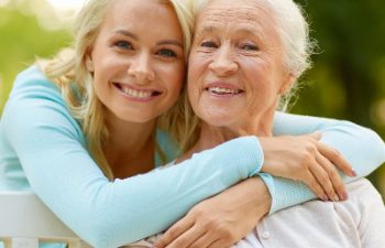 A young woman hugging an elderly woman in a park.