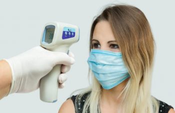 A woman is holding an infrared thermometer.