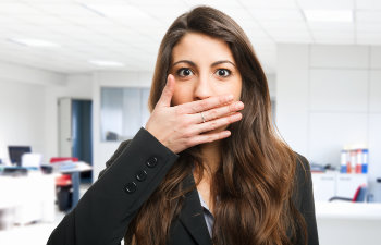 A businesswoman covering her mouth with her hand because of bad breath.