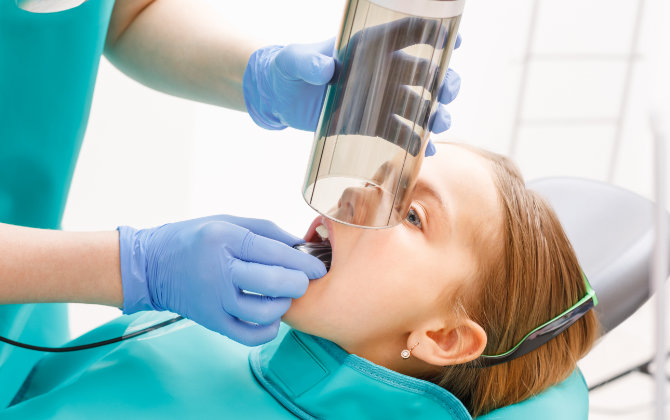 A young girl getting dental imaging with the use of digital sensors.