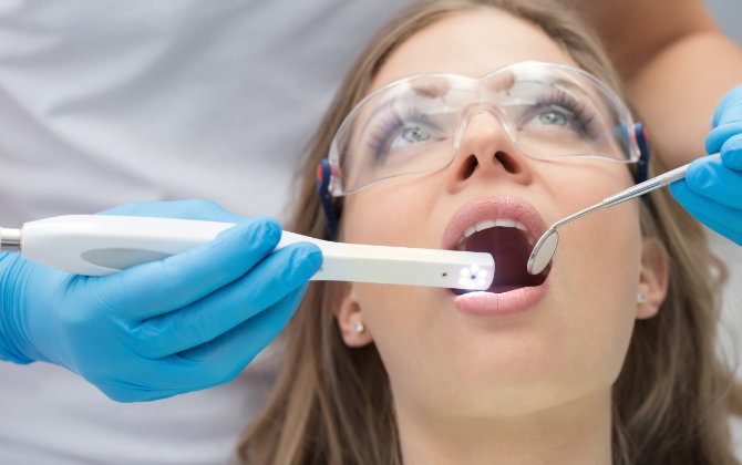 A female patient and a dentist using an intraoral camera for dental check-up and oral screening.