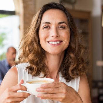 mature smiling woman holding a cup of coffee
