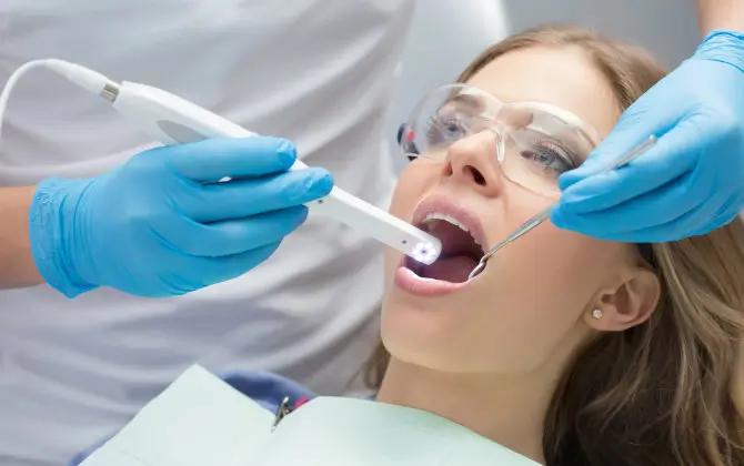 Female dental patient undergoing oral screening with an intraoral camera.