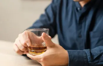 male hand holding a glass of alcohol