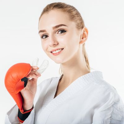 Smiling Female Karate Fighter Holding Mouthguard Isolated