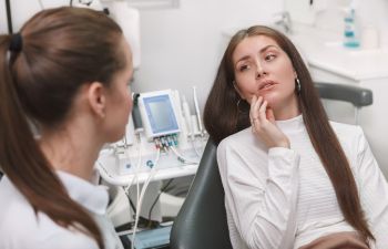 A dentist consulting a woman with dental issue caused by untreated cavities